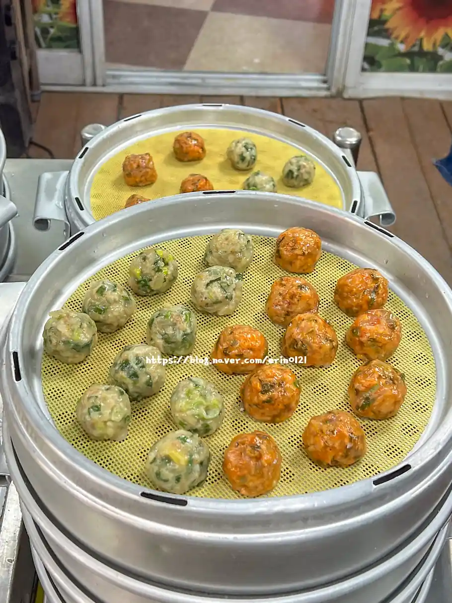 한국 강릉의 푸른 바다를 배경으로 나무 테이블 위에 화려하게 플레이팅된 신선한 모둠회와 다양한 곁들임 찬이 놓여 있는 고화질 사진