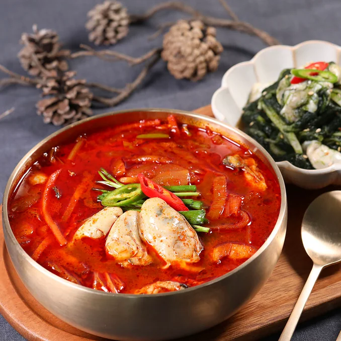 한국 식당 테이블 위에 정갈하게 차려진 굴코스 요리와 다양한 밑반찬이 놓인 항공샷